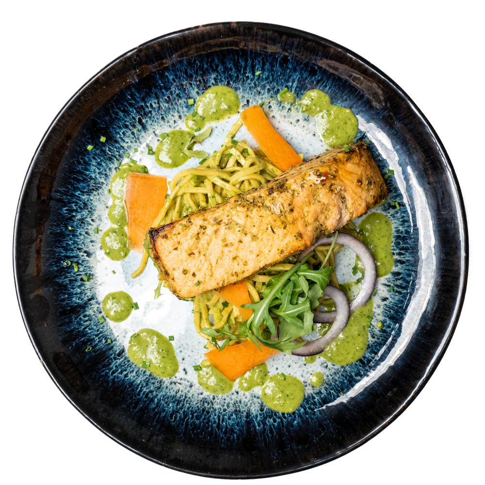 Delicious salmon fillet on a bed of noodles, garnished with fresh herbs, vegetables, and topped with a vibrant green sauce on an elegant plate