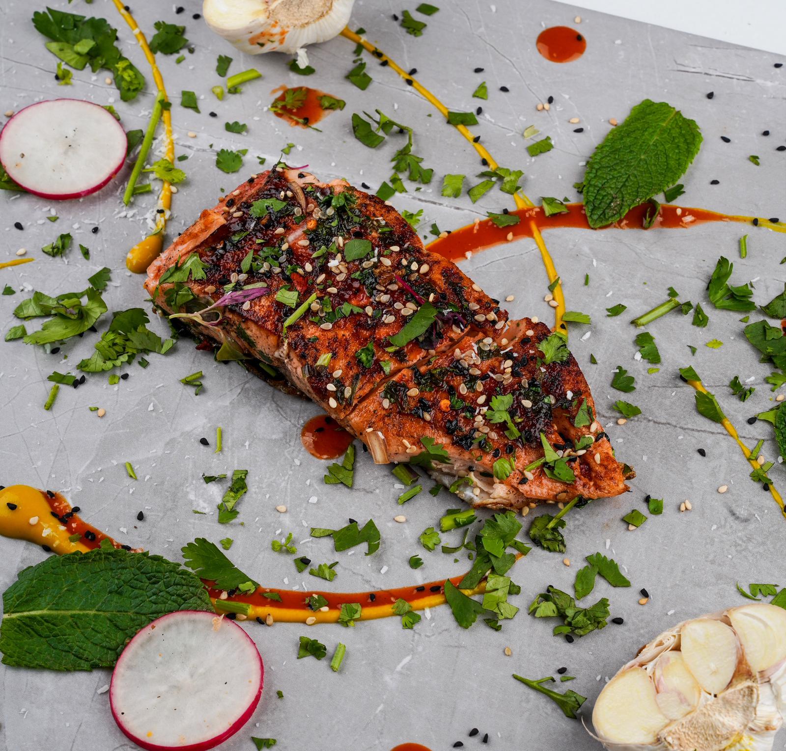 Chef-prepared fish meal on a slate plate with garnish and sauce, high-protein low-carb corporate meal